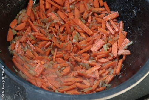 Carrots are stewed in a cauldron. Dishes cooked on fire. Eastern cuisine. Close-up. Selective focus. Copyspace