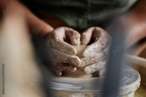 Front view closeup of female hands creating earthenware carefully shaping clay on pottery wheel copy space