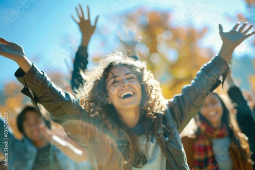 Portrait of happy young woman with raised hands and friends in background photo