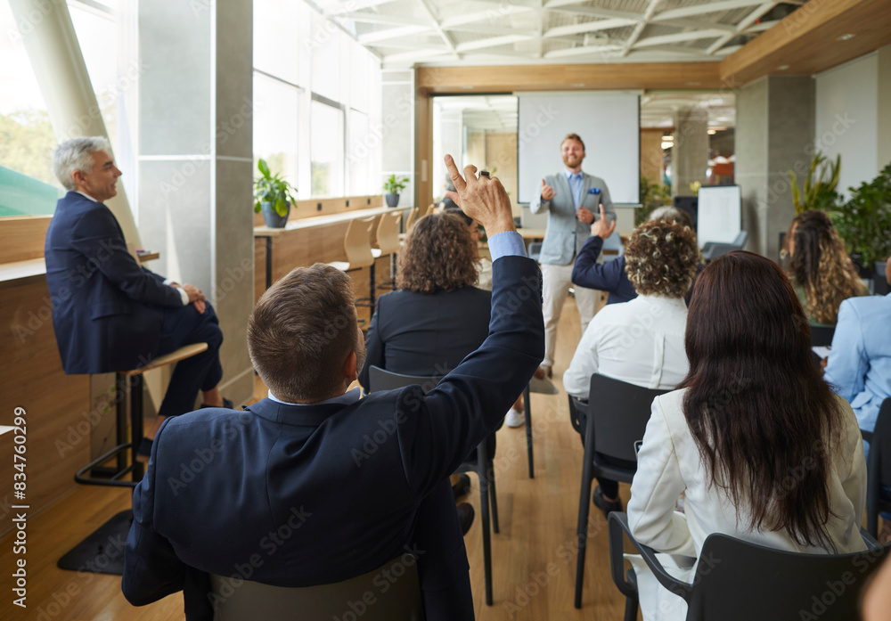 © Studio Romantic - Young colleagues raising hands to ask questions during business meeting sitting back in office. Diverse business people voting at the conference in meeting room listening their speaker. © Studio Romantic - Young colleagues raising hands to ask questions during business meeting sitting back in office. Diverse business people voting at the conference in meeting room listening their speaker.