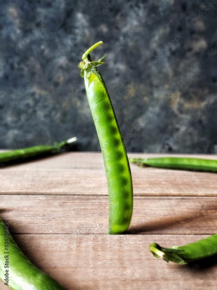 Rustic still life with Green Peas. Grains of sweet Peas are Translucent in the light. Rural style vertical photo can used social media, postcard, card, poster print.