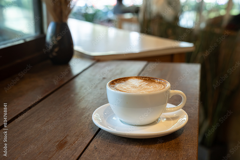 Hot coffee latte with latte art milk foam in cup mug on wood desk on top view. As breakfast In a coffee shop at the cafe,during business work concept,vintage style Hot coffee latte with latte art milk foam in cup mug on wood desk on top view. As breakfast In a coffee shop at the cafe,during business work concept,vintage style