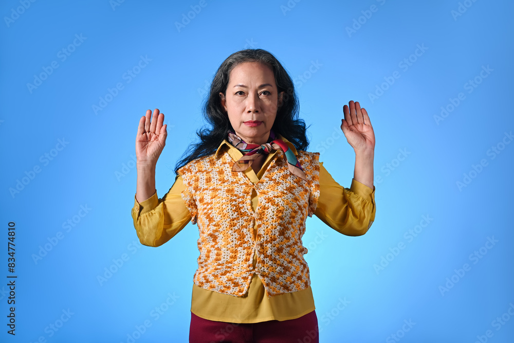 Portrait of stylish senior woman with surprise expression isolated over blue background
