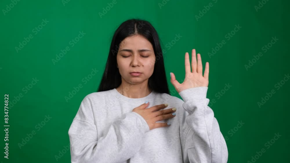 Promise of trust. Young woman places her hand on her chest in a studio shot, symbolizing faith, honesty, and loyalty. An expression of hope, truth, and honour Promise of trust. Young woman places her hand on her chest in a studio shot, symbolizing faith, honesty, and loyalty. An expression of hope, truth, and honour