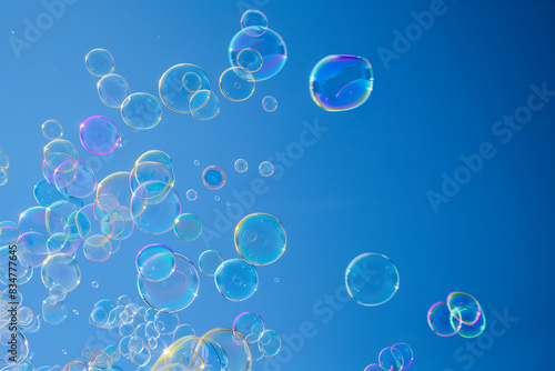 Sfondo azzurro cielo con bolle di sapone iridescenti che volano sospese in aria photo