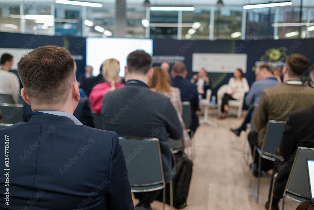 Fototapeta premium Business professionals attending a conference, listening to speakers in a modern indoor setting. Networking, education, and collaboration atmosphere.