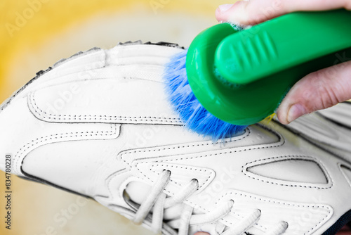 Close up of cleaning white sneakers with a brush and detergent in a basin. © Natallia