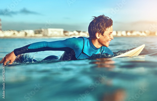 Teenager, boy and surfing with waves, beach and happiness for fitness, getaway trip and cheerful. Surfer, athlete and vacation with holiday, adventure and sunshine in ocean for sports and excited photo