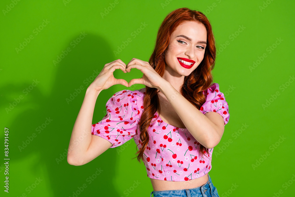 Photo of adorable lovely girl wear pink blouse showing arms heart empty space isolated green color background Photo of adorable lovely girl wear pink blouse showing arms heart empty space isolated green color background