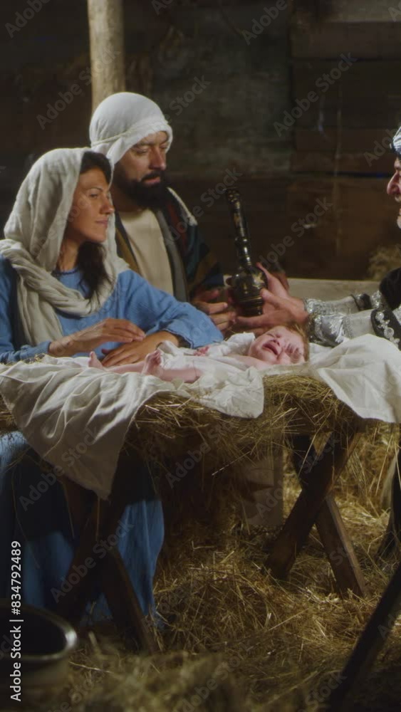Zoom in view of Mary and Joseph receiving gifts from Wise Men near manger with son of God in stable in Bethlehem. Vertical shot. Zoom in view of Mary and Joseph receiving gifts from Wise Men near manger with son of God in stable in Bethlehem. Vertical shot.