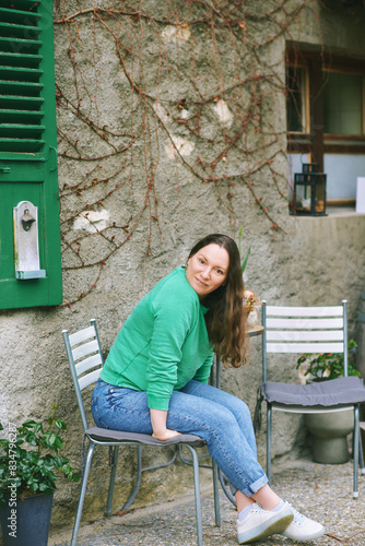 Outdoor portrait of 40 year old woman with brown hair, wearing green sweatshirt