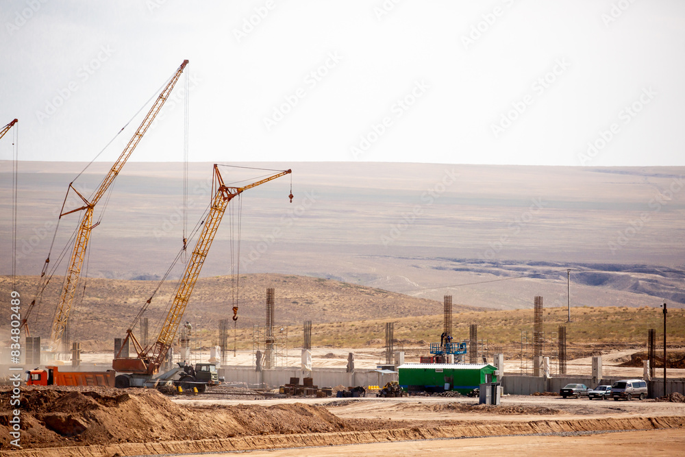 Lifting cranes and other equipment at a construction site. A group of lifting platforms for construction and loading and unloading operations. Construction at the initial stage. Lifting cranes and other equipment at a construction site. A group of lifting platforms for construction and loading and unloading operations. Construction at the initial stage.