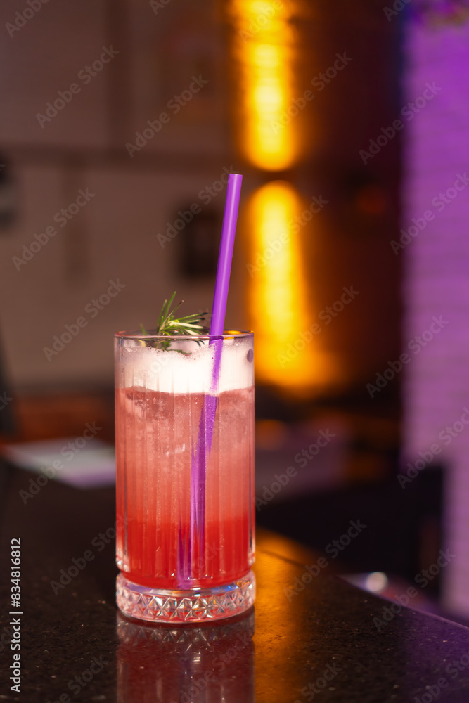 Close-up of a strawberry alcoholic cocktail in a glass with foam decorated with a sprig of rosemary and a straw stands on the bar counter in a beautiful modern bar, copy space. Vertical photo Close-up of a strawberry alcoholic cocktail in a glass with foam decorated with a sprig of rosemary and a straw stands on the bar counter in a beautiful modern bar, copy space. Vertical photo