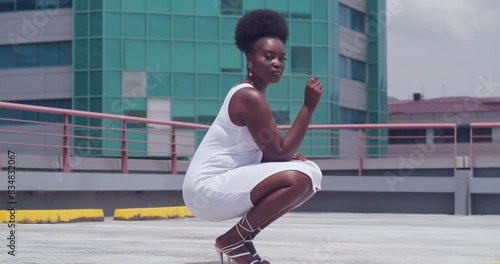 On a rooftop overlooking the city, a young black girl wears a white dress. photo