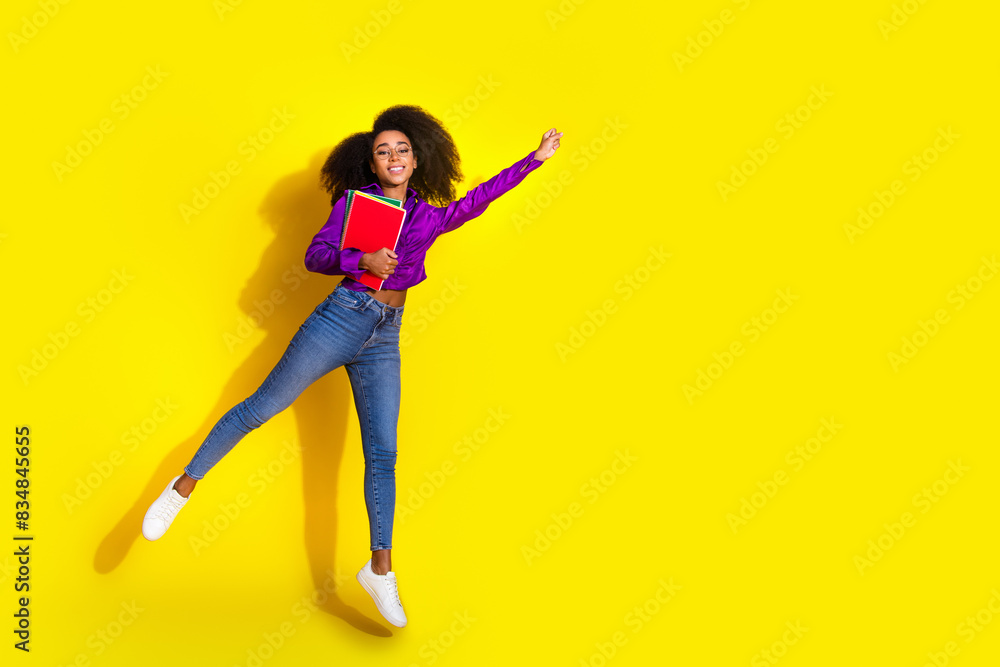 Full body photo of attractive young woman hold books flying superhero dressed stylish violet clothes isolated on yellow color background