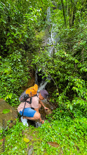 Man Exploring Waterfall in Dense Tropical Forest