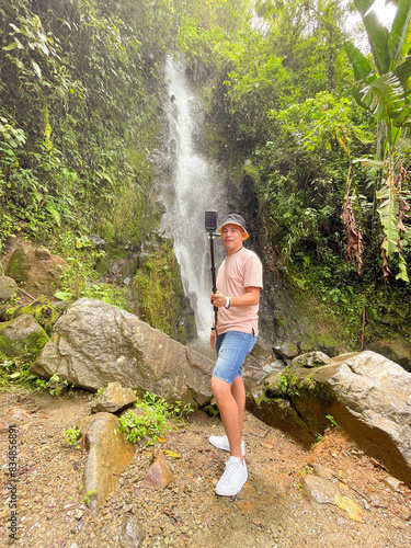 Man with Camera Stick in Tropical Forest by Waterfall