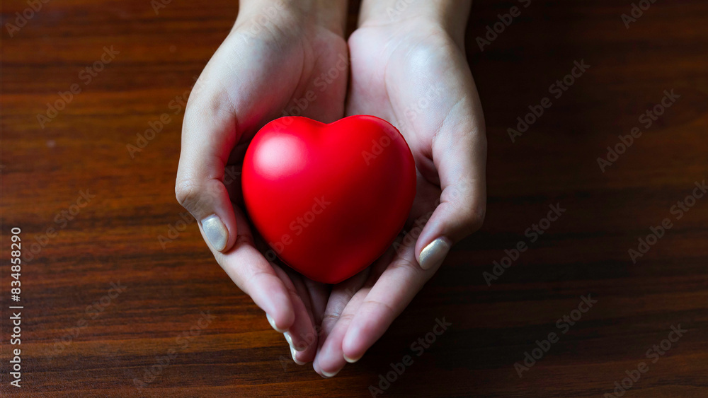 A young woman holds a red heart on a light blue background, top view with ample space for text. Perfect for donation themes. A young woman holds a red heart on a light blue background, top view with ample space for text. Perfect for donation themes.