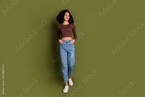 Full length photo of lovely young lady walk look empty space dressed stylish brown garment isolated on khaki color background