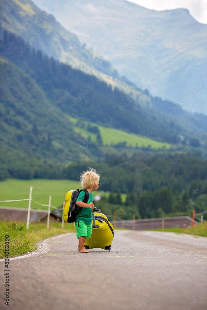 Little children, boy brothers with backpacks and sutcase, travel on the road to scenic mountains, summertime Little children, boy brothers with backpacks and sutcase, travel on the road to scenic mountains, summertime