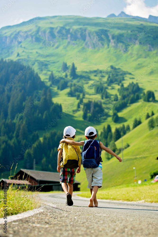 Two little children, boy brothers with backpacks travel on the road to scenic mountains Two little children, boy brothers with backpacks travel on the road to scenic mountains