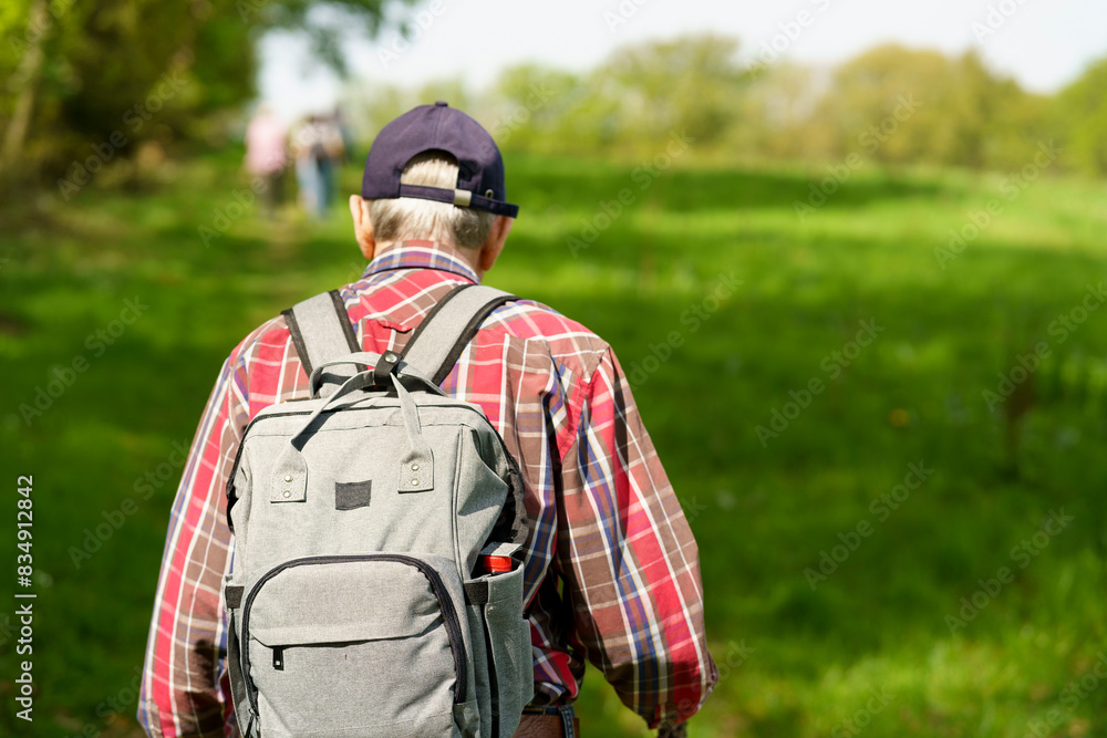 Rear view of senior man with backpack standing in the countryside. Rear view of senior man with backpack standing in the countryside.