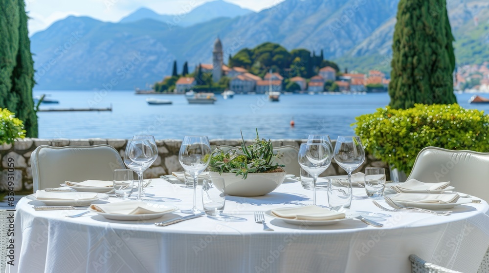 Fototapeta premium colorful flowers positioned in front of an open window adorned with blue shutters, offering a scenic view of the sea, a charming house, and a clear sky on a picturesque island.