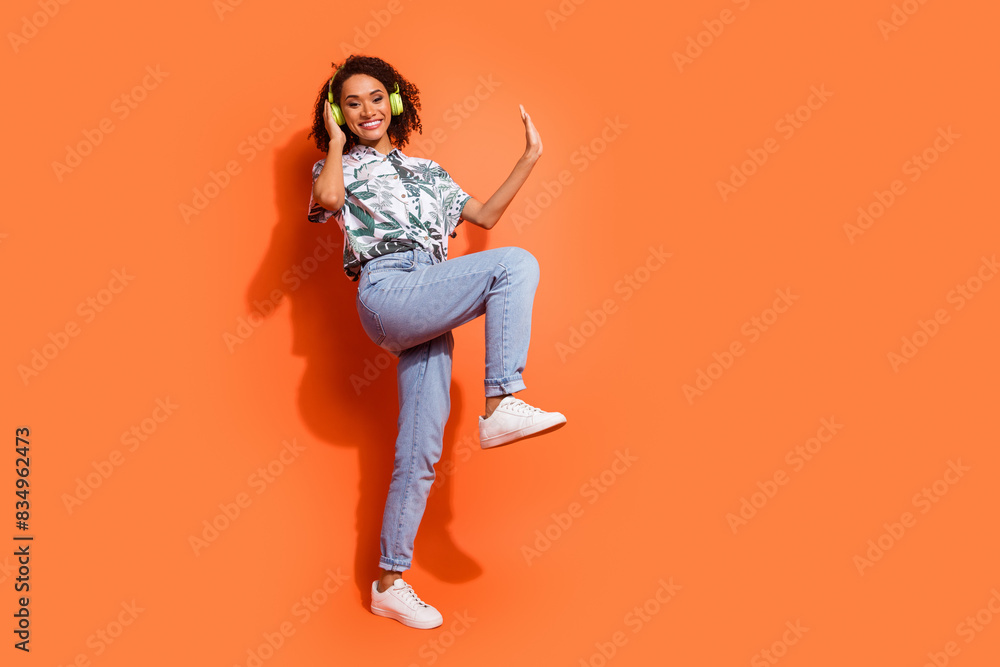 Photo portrait of brown wavy haired girl wear summer shirt listen audio playlist in bluetooth earphones dancing isolated on orange color background Photo portrait of brown wavy haired girl wear summer shirt listen audio playlist in bluetooth earphones dancing isolated on orange color background