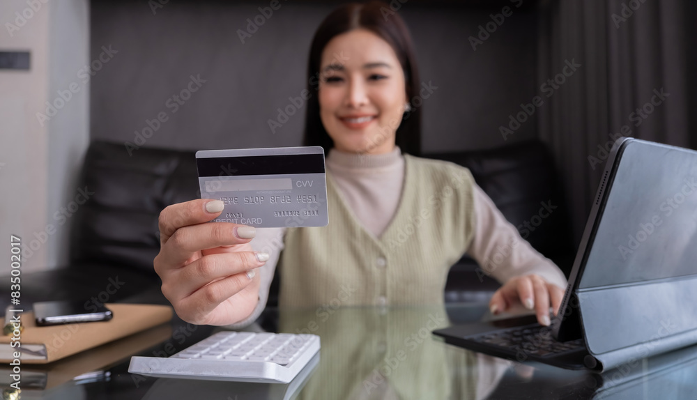 Asian woman holding credit card and using tablet at home. Concept of online shopping and digital payments Asian woman holding credit card and using tablet at home. Concept of online shopping and digital payments