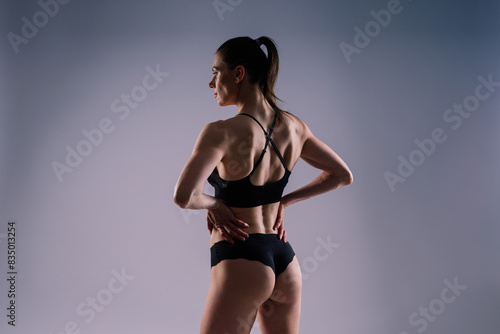 Fit sportswoman in leggings and sports bra looking away and while standing on yellow red