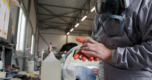 Technician in protective gear holding a paint spray gun, preparing to paint a car in an auto repair workshop. Auto Repairman Holding Paint Spray Gun in Workshop. Car Painter in Auto Body Shop photo