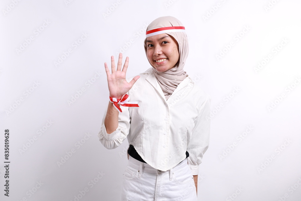 Asian young asian muslim woman with red white ribbon for celebrating Indonesia independence day standing while showing five fingers Asian young asian muslim woman with red white ribbon for celebrating Indonesia independence day standing while showing five fingers