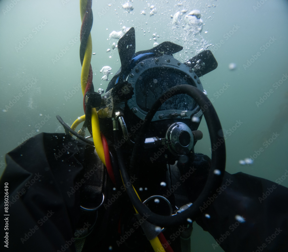 Commercial diver in helmet working underwater Commercial diver in helmet working underwater