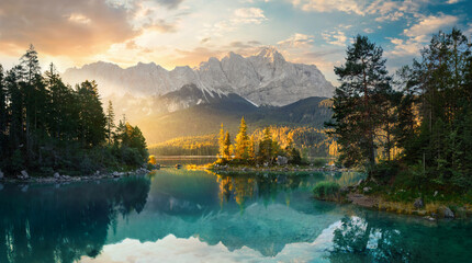 Glasbilder Natur Painterly lake scenery in Germany with mountains reflected in the teal water and a beautiful ray of morning sunlight illuminating some trees   © Smileus