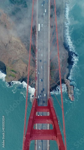 Vertical Screen: Create a visually striking vertical video showcasing the fogenveloped Golden Gate Bridge from a birdseye view, highlighting its allure, distinctiveness, and remarkable architecture photo