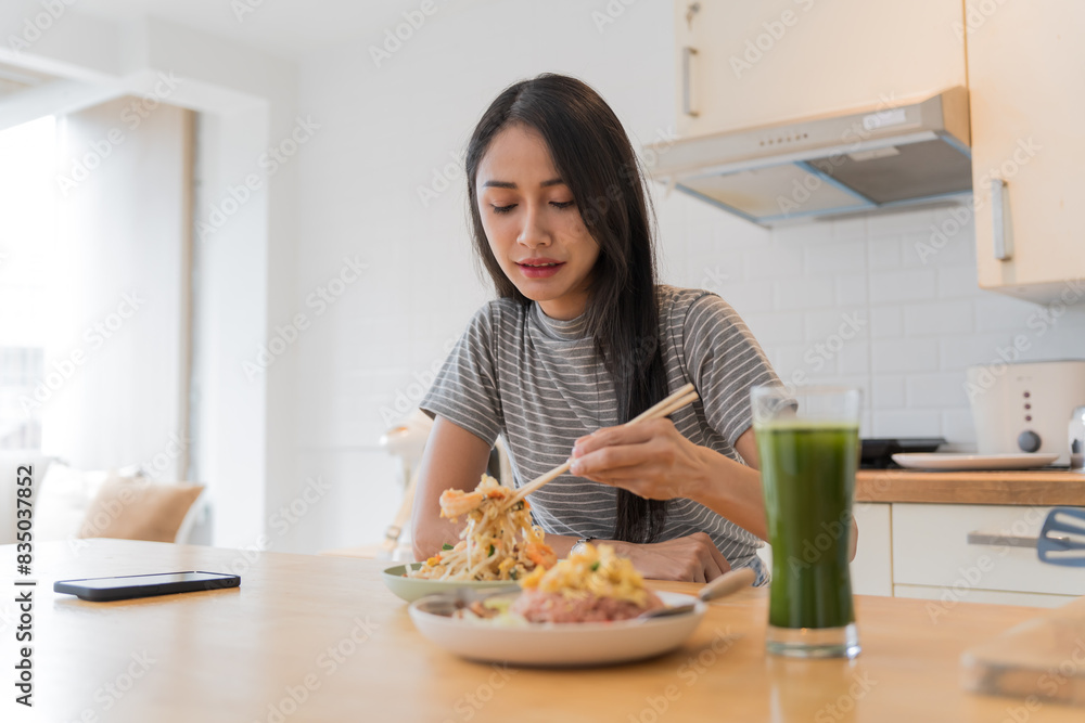 Asian Girl eating Thai food in kitchen counter Home delivery food feeling happy Asian Girl eating Thai food in kitchen counter Home delivery food feeling happy