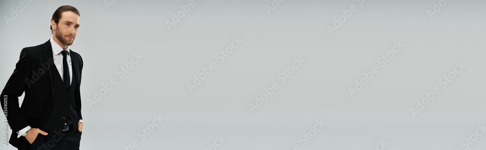 Handsome, bearded businessman in suit and tie stands confidently with hands in pockets on a grey studio background. Handsome, bearded businessman in suit and tie stands confidently with hands in pockets on a grey studio background.