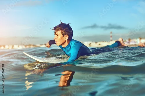 Obraz Kid, waves and surfing at beach for holiday, sports and wellness with board, blue sky and swimsuit. Boy, workout and swimming stroke or surfer for learning, fitness and summer while on vacation