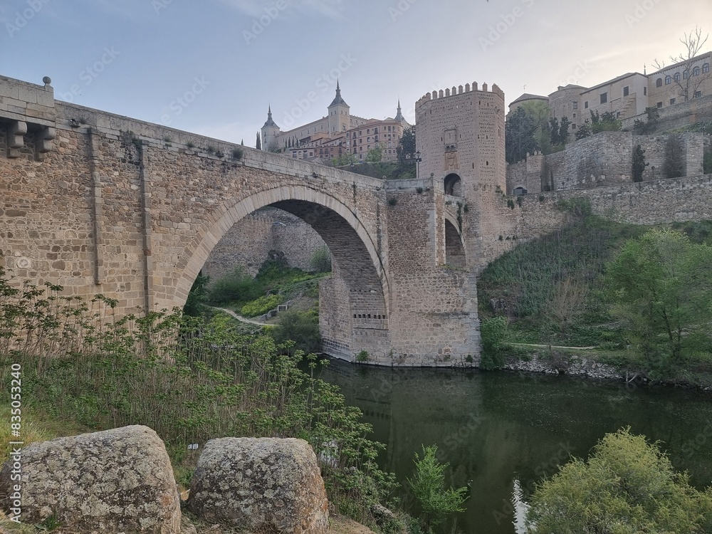 Toledo, Spain, bridge, ancient castle and towers, cathedral on the background, river and green on the frontend Toledo, Spain, bridge, ancient castle and towers, cathedral on the background, river and green on the frontend