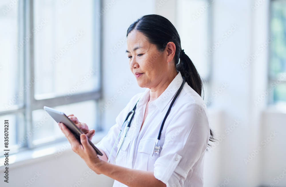 Focused Female Doctor Using Digital Tablet in Bright Hospital Corridor Focused Female Doctor Using Digital Tablet in Bright Hospital Corridor