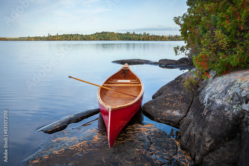 Red wood canoe on rocky shore of a Boundary Waters lake in morning light during autumn