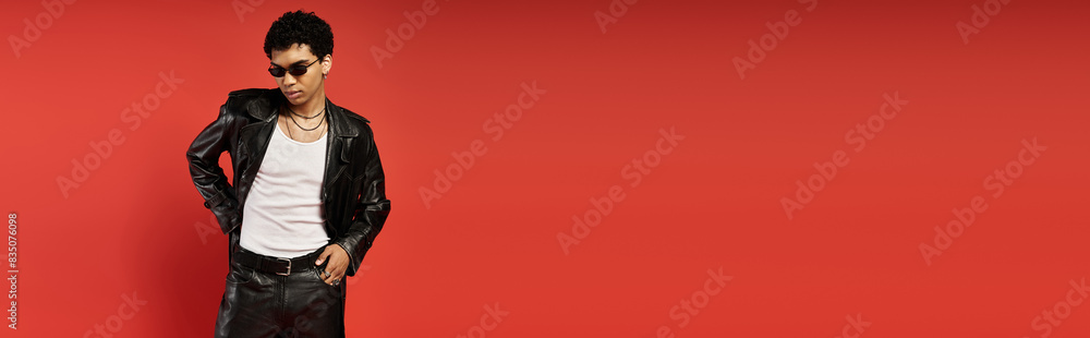 Handsome man in leather jacket and sunglasses striking a pose against vibrant red backdrop. Handsome man in leather jacket and sunglasses striking a pose against vibrant red backdrop.