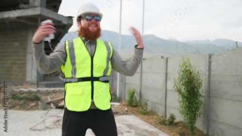 Happy engineer contractor dancing on construction site in good mood, crazy bearded worker, calls you to dance. photo