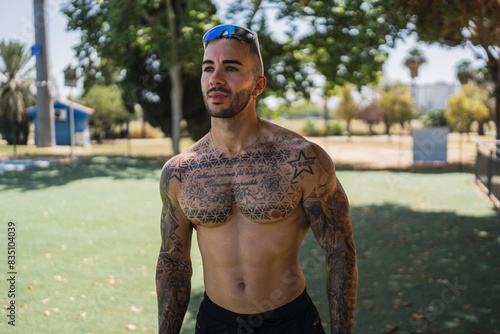 Chico joven musculoso y tatuado en pista de atletismo posando con ropa deportiva photo