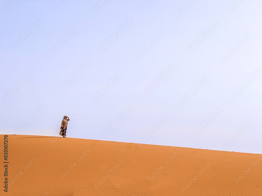 Traveler Standing on a Vast Sand Dune in Merzouga Desert Traveler Standing on a Vast Sand Dune in Merzouga Desert