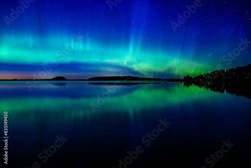 Northern lights dancing over calm lake in Farnebofjarden national park in north of Sweden. photo