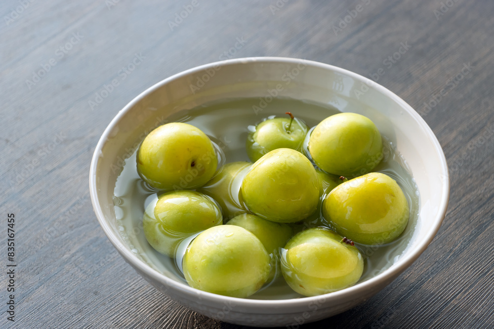Green plums in a white porcelain bowl, photographed in Shanghai, China Green plums in a white porcelain bowl, photographed in Shanghai, China