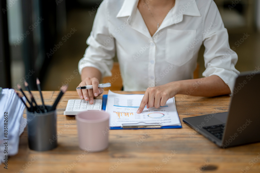 A woman is sitting at a desk with a laptop and a stack of papers A woman is sitting at a desk with a laptop and a stack of papers