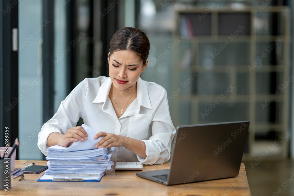 A woman is sitting at a desk with a stack of papers in front of her A woman is sitting at a desk with a stack of papers in front of her