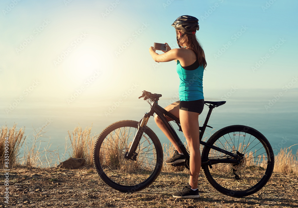 Fototapeta premium Woman, cyclist and outdoor with photography of view for travel blog, memory and social media post or content creation. Girl, smartphone and mountain for trail riding, cycling and adventure on holiday